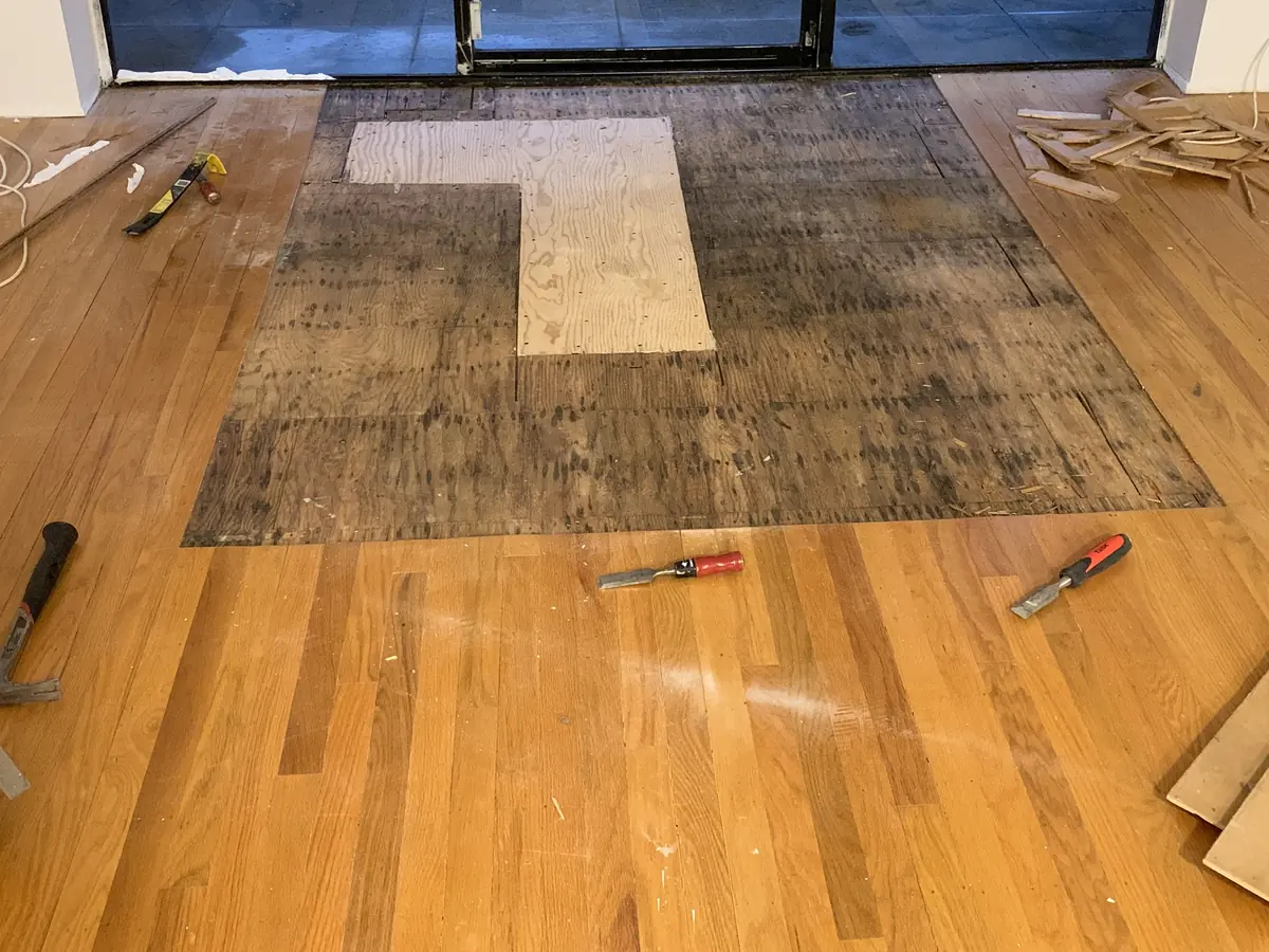 A hall floor part-way through sanding, bare wood beside the old finish